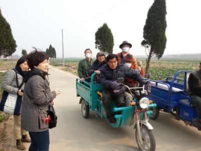 写真・図版 : 崇明島の農村で電動三輪車に試乗する日本からの参加者（高木晴光さん提供）