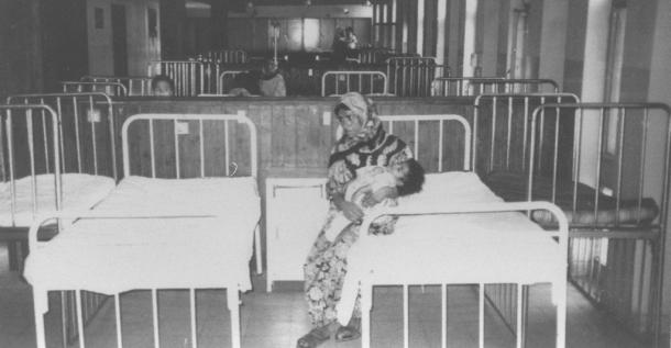 写真・図版 : 空きベッドが増えたバグダッドの国立病院で、栄養失調の子供を抱く母親＝1995年11月、サダム・シティーのカーデシーア病院で、撮影・筆者