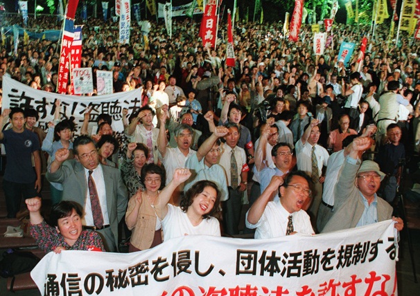 シュプレヒコールをあげ、通信傍受法の廃案を訴える人たち＝1999年6月、東京都千代田区の日比谷公園
