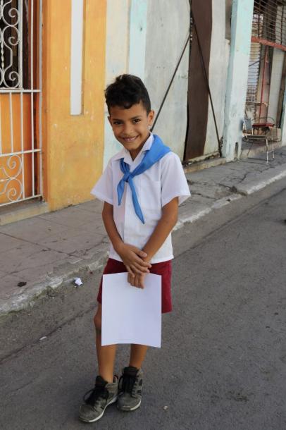 写真・図版 : 小学生の制服の男の子。手に持っているのは、テストか、成績の紙?　シャイな笑顔は、「いい成績」だった証拠?　 両親とのんびり歩いていた＝撮影・筆者