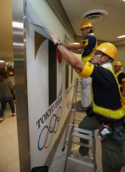 写真・図版 : 五輪エンブレムをはがす作業員ら＝2015年9月2日、千葉県の成田空港