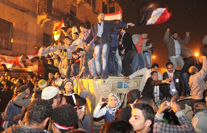 写真・図版 : アラブの春、ムバラク大統領の退陣後、軍の装甲車に上がって喜び合う市民たち＝2011年2月11日、エジプト・カイロのタハリール広場