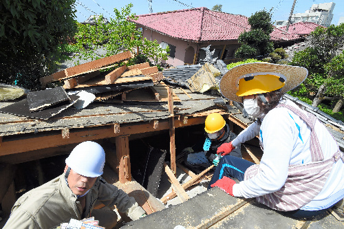 写真・図版 : 崩れた家の屋根に穴を開け、部屋の中から物を取り出す住民＝4月17日、熊本県益城町、白井伸洋撮影