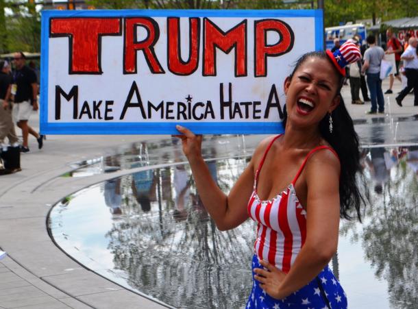 「トランプは米国を再びヘイトにする」というカードを見せて抗議活動をする女性＝真鍋弘樹撮影