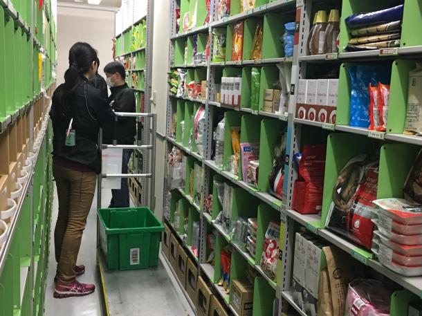 アマゾンの「プライムナウ」向け倉庫。注文された商品を作業員が一つずつ集めていく＝東京都内