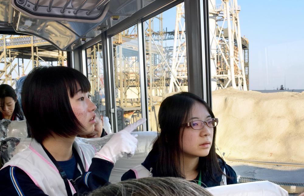 写真・図版 : 廃炉現場を見学する福島高校の生徒たち。後ろは水素爆発した１号機の原子炉建屋＝2016年11月18日、川原千夏子撮影