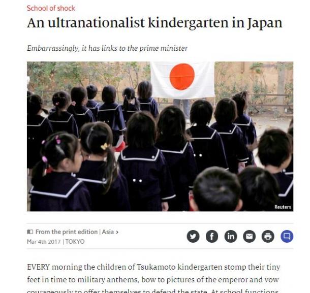 写真・図版 : 日の丸の旗の前に並ぶ塚本幼稚園の児童の姿（英エコノミストのウェブサイトより）