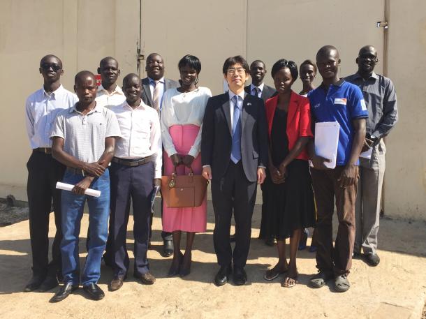 写真・図版 : ジュバの日本大使館前で、来日を前に紀谷昌彦・駐南スーダン大使を囲む研修生たち＝ニコラス・ワニ氏提供