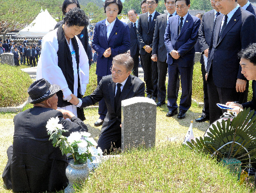 写真・図版 : 光州事件の追悼行事で、墓地の前で遺族を慰問する文在寅大統領（中央）＝2017年5月18日、ロイター