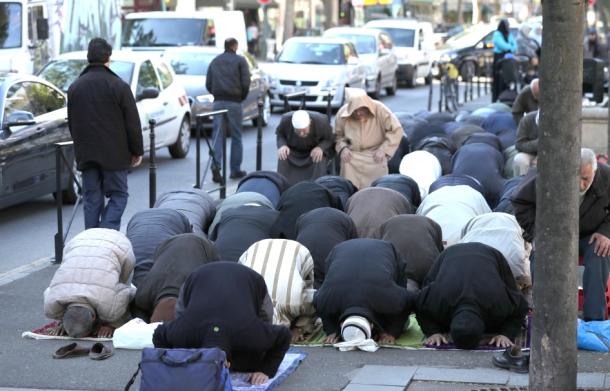 モスクを閉鎖され、抗議の意味も込め、路上で祈りを捧げるイスラム教徒の人たち＝１９日午後、パリ郊外クリシー市
