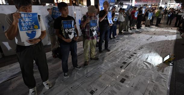 路上にヘイトスピーチが書かれたツイートを敷き詰めて踏みつける参加者。歩行者にもツイートを踏んで通るよう呼びかけていた＝８日午後６時２５分、東京都中央区