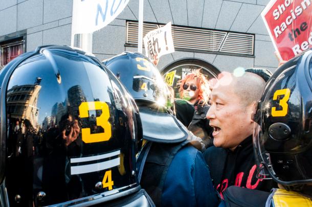 在特会などの極右、排外デモへのカウンター行動。排外主義者のデモ隊へ機動隊に囲まれながら抗議するECDさん＝2014年3月16日、東京・池袋（写真家・島崎ろでぃー撮影）

