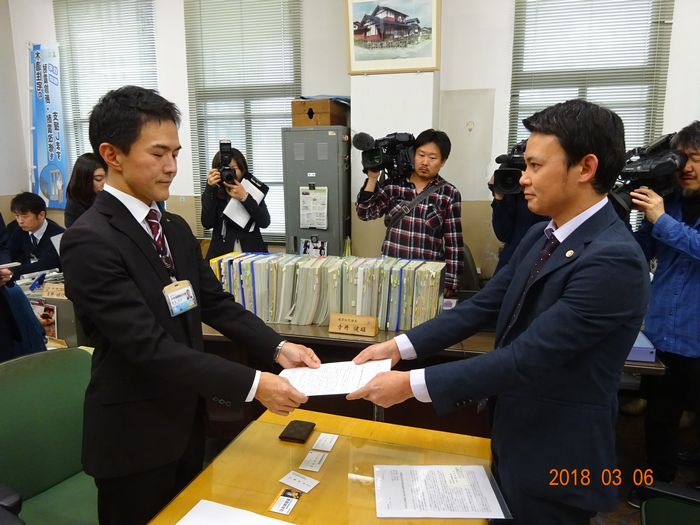 写真・図版 : 富山県の担当者に要望書を渡す「反-貧困ネットワークとやま」の関係者（右）＝3月6日、「反-貧困ネットワークとやま」提供
