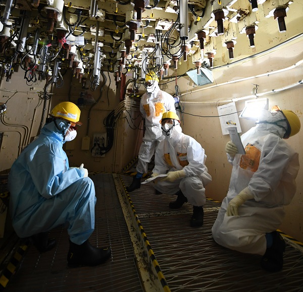 5号機の原子炉直下にある作業用足場で、東京電力の担当者（左）から格納容器内部調査の様子を聞いた＝5月24日、松尾一郎撮影
