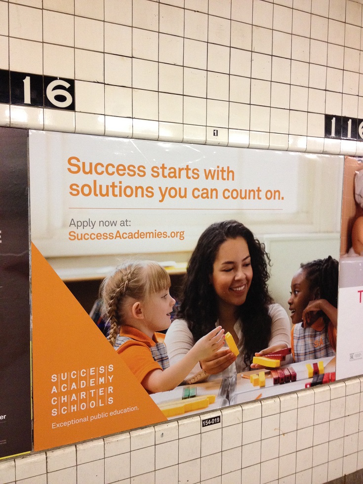 写真・図版 : ハーレムでは、生徒数拡大を狙う公設民営学校の宣伝が至る所に見られる。この写真は地下鉄のホーム＝2015年12月、米ニューヨーク（著者撮影）
