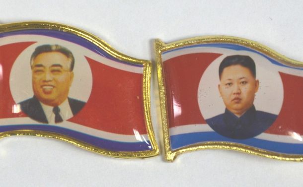 写真・図版 : 北朝鮮と国境を接する中国側で売られていた金正恩のバッジ（右）。左は故金日成のバッジ