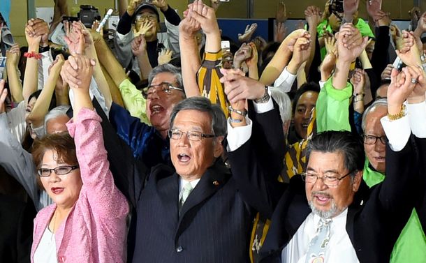 写真・図版 : Takeshi Onaga (center), Okinawa's governor-elect, and his supporters raise their hands ('banzai' celebration) in Naha, Nov.16 2014