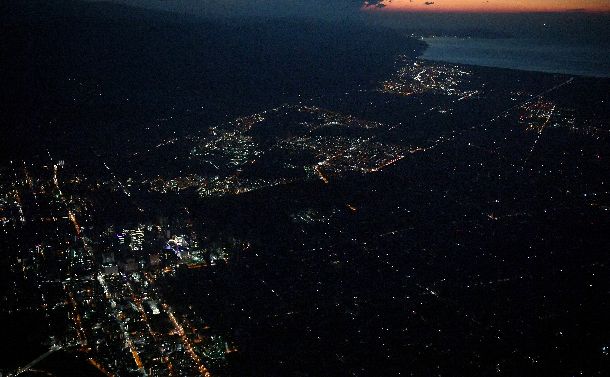 写真・図版 : 夜を迎え停電したままの札幌市内の住宅地（右）。JR札幌駅周辺（中央左）も暗いままだ＝2018年9月6日