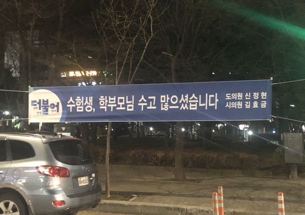 写真・図版 : ソウル市内の公園に張られた垂れ幕。「受験生、学父母(様)お疲れ様でした」と書かれている（筆者撮影）