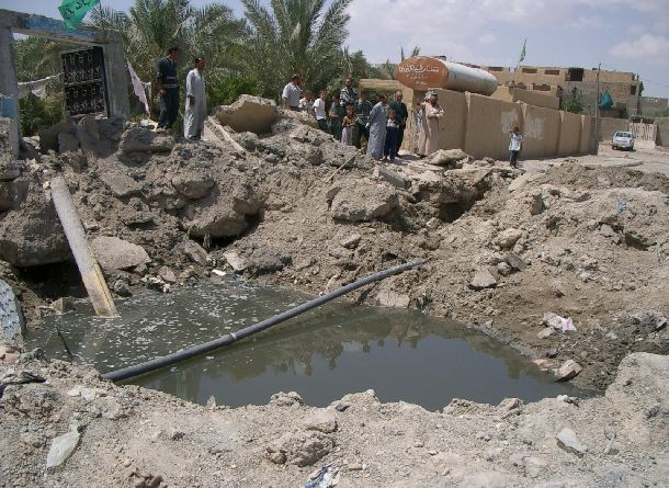 イラク戦争の米軍の爆弾によってできた大きな穴。埋設されていた水道管が破壊され、水がたまっていた＝2004年5月5日、ファルージャ