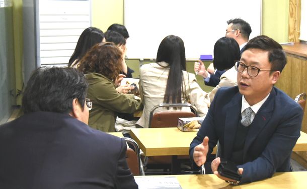写真・図版 : 大手ギョーザチェーン店が開いたフランチャイズ方式の出店説明会で、担当者（右）から熱心に説明を聴く参加者ら＝2017年4月19日、ソウル