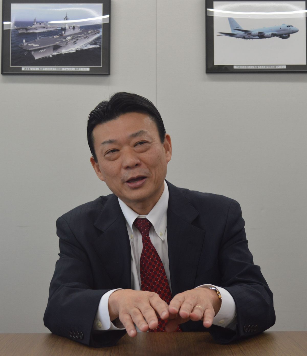 写真・図版 : 質問に答えるFRONTEOの守本社長。元海上自衛官で、部屋には海自のP1哨戒機や、護衛艦の「いせ」と「ひゅうが」の写真があった＝3月26日、東京都港区の同社