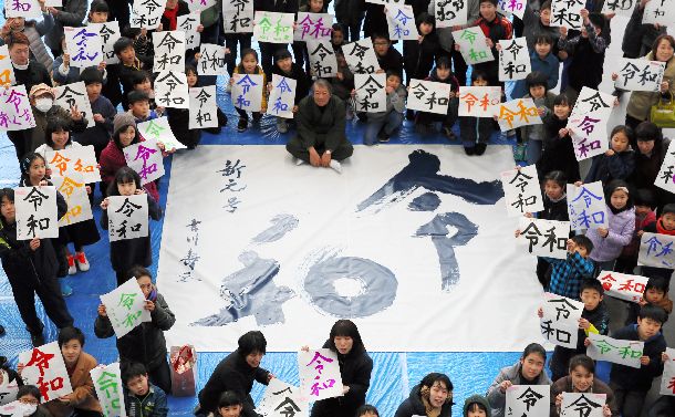 新元号「令和」書き初め祭り。書家の吉川壽一さんの書を囲み、参加者は思い思いの色で書いた新元号「令和」を掲げた＝2019年4月2日、福井市 
