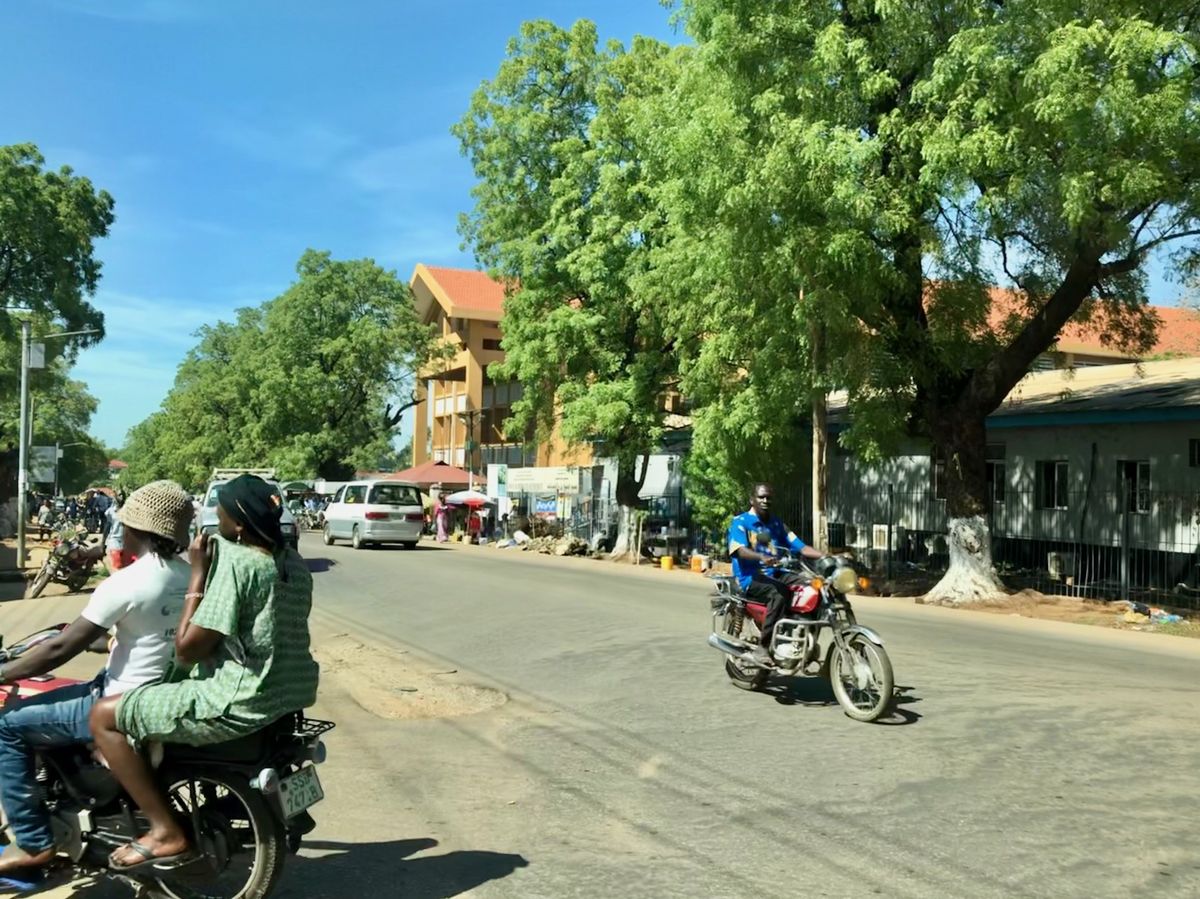 写真・図版 : ジュバの市内の舗装道路は少しずつ増えてきている。バイクのヘルメットはしていない人がほとんど。