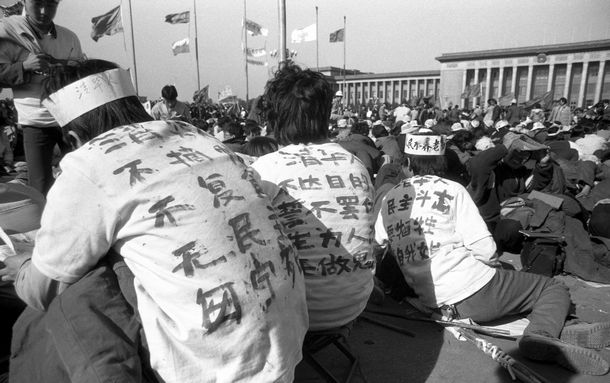 写真・図版 : 1989年5月に劉建氏が撮った天安門広場の一コマ。標語を書いたＴシャツを着た清華大の学生が座り込んでいる＝劉建氏提供