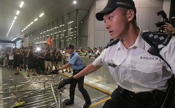 写真・図版 : 香港立法会で鉄柵を投げつけるデモ隊の参加者とにらみ合う警察官＝2019年6月10日