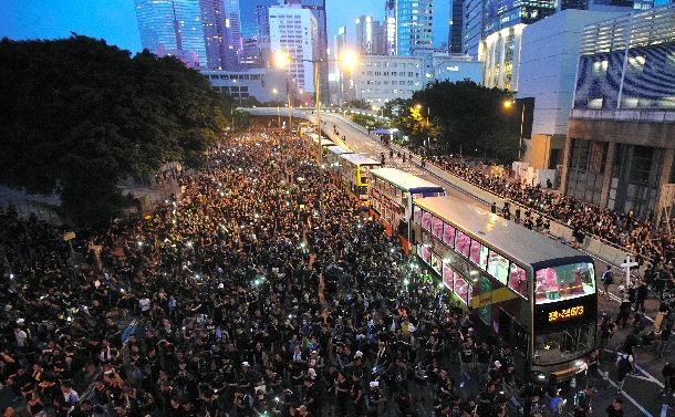 写真・図版 : デモ参加者が車道になだれ込み、身動きがとれなくなったバス＝2019年6月16日、香港