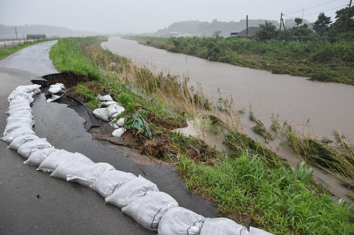 写真・図版 : 大里川(右)が増水して一部が崩落した道路=鹿児島県いちき串木野市