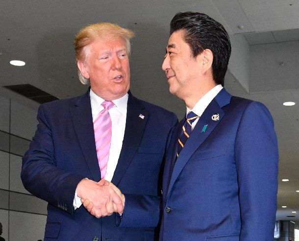 写真・図版 : 「G20」サミットでトランプ米大統領を出迎え握手する安倍晋三首相（右）＝2019年6月28日、大阪市住之江区のインテックス大阪