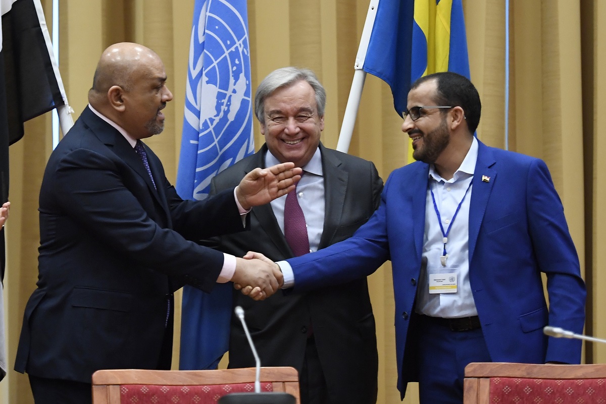写真・図版 : 2018年12月、国連のグテーレス事務総長(中央)を間に挟み、ハディ暫定政権のヤマニ外相(左)とフーシ側代表のアブドルサラム氏が停戦合意で握手を交わしたのだが……=AP