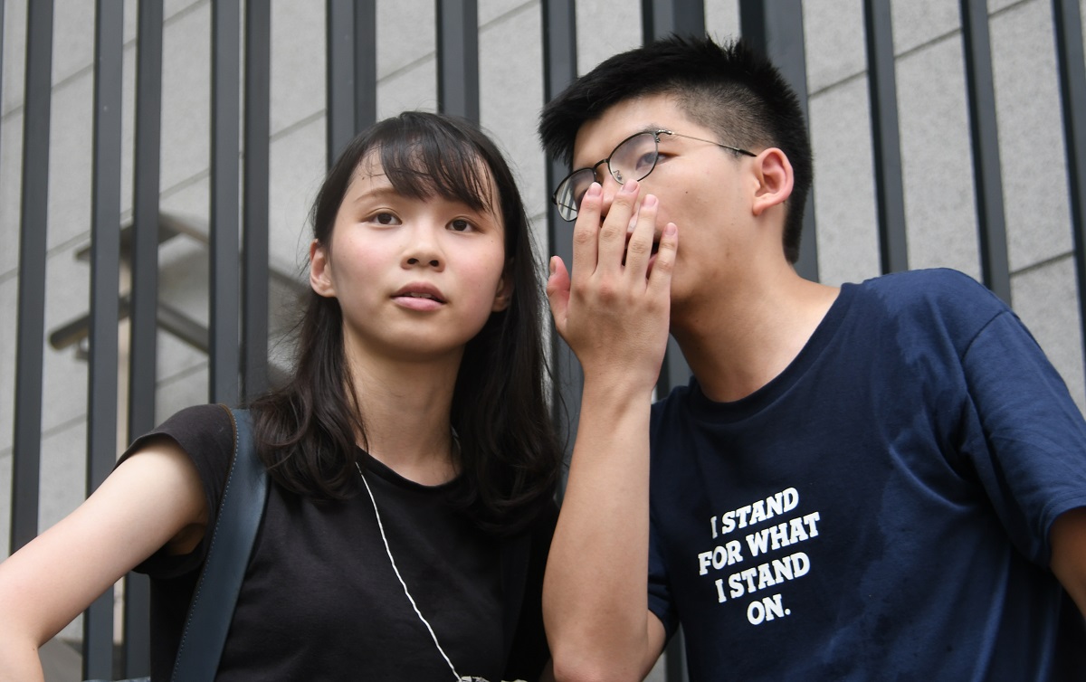 写真・図版 : 一時拘束された黄之鋒氏(右)と周庭氏=2019年6月