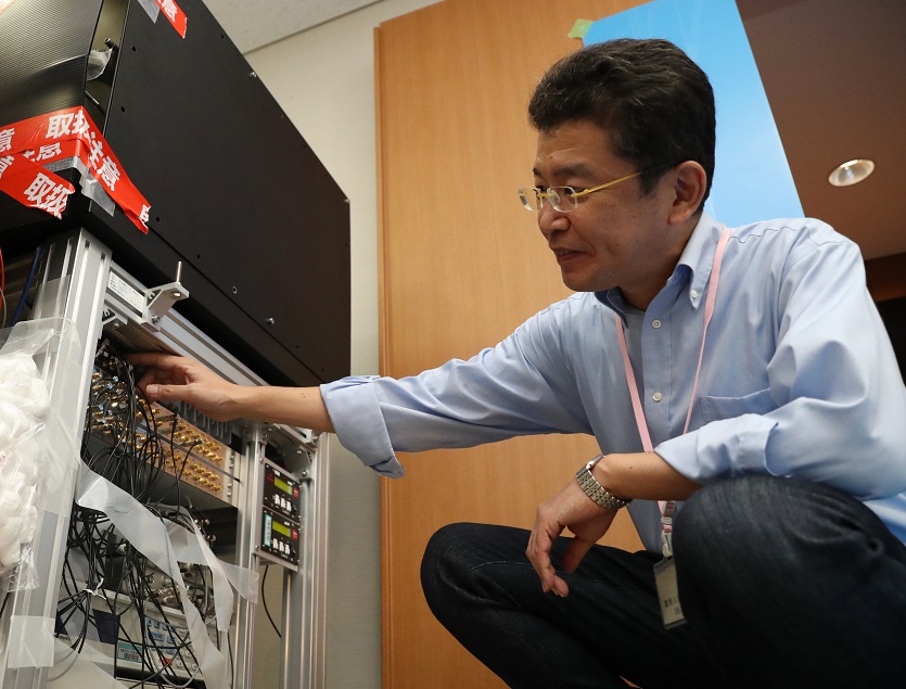 写真・図版 : 東京スカイツリーの上と下で時間の流れに差があるかの検証実験に入る前の光格子時計（左）と東京大の香取秀俊教授＝2018年10月2日、東京都墨田区、池田良撮影 