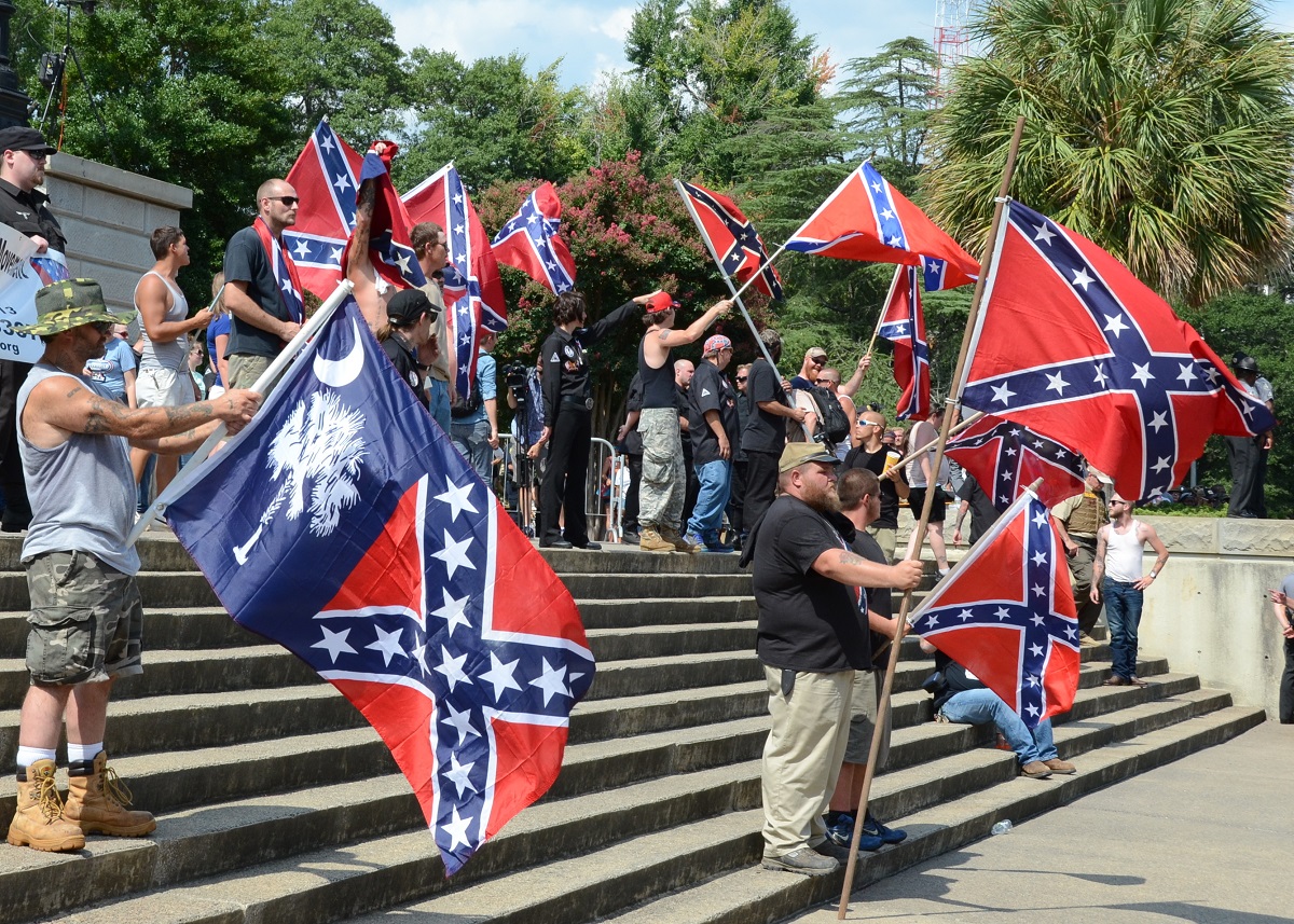 写真・図版 : 白人至上主義団体「クー・クラックス・クラン」が呼びかけた集会に参加し、「南軍旗」を掲げる人たち＝2015年7月18日、米サウスカロライナ州コロンビア
