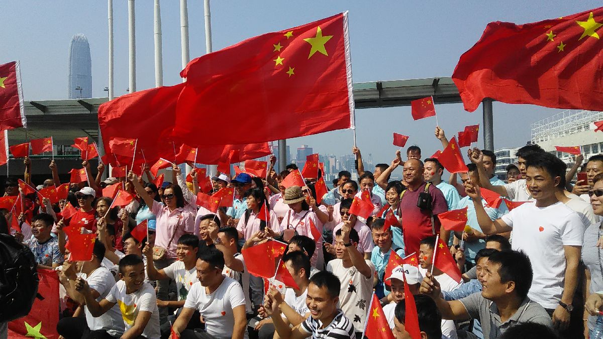写真・図版 : 中国国旗の五星紅旗を振る香港市民＝2019年10月1日、香港の九龍半島尖沙咀、筆者撮影