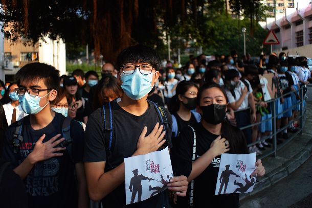 写真・図版 : 警察官に発砲された高校生が通う学校の前に集まり、撃たれた左胸付近に手を置き抗議の声を上げる若者たち＝2019年10月2日、香港・荃湾（ワン）、竹花徹朗撮影