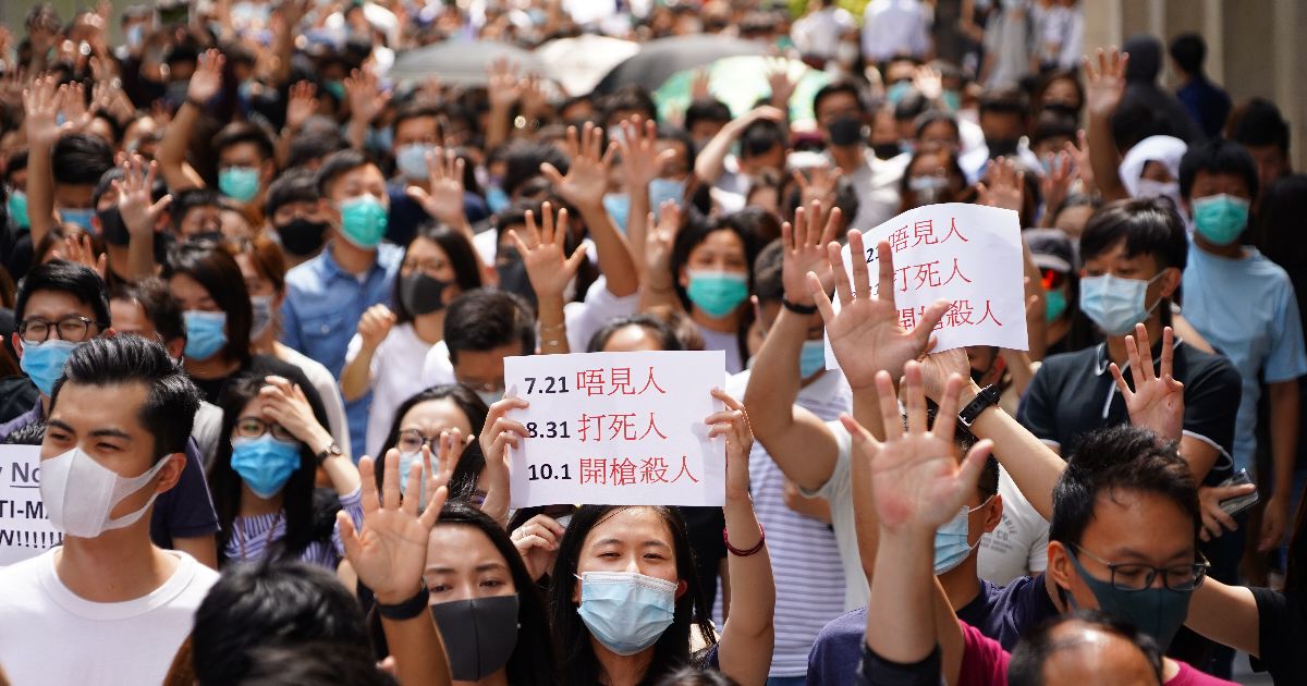 写真・図版 : 覆面禁止法に反対し繁華街を練り歩くデモ隊。多くの参加者が顔を隠すマスクなどをして声を上げた＝2019年10月4日、香港、竹花徹朗撮影  

