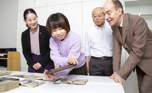 写真・図版 : 本を刷った版木を手に取る日本画家の松平莉奈さんと国文学研究資料館のロバート キャンベル所長（右端）。右から2人目は同館の入口敦志教授、左端は筆者