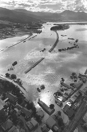 写真・図版 : 千曲川の決壊は繰り返されてきた。1983年9月の台風禍の大雨による決壊で、水浸しになった長野県飯山市の住宅地＝朝日新聞社ヘリから、朝日新聞写真部撮影
