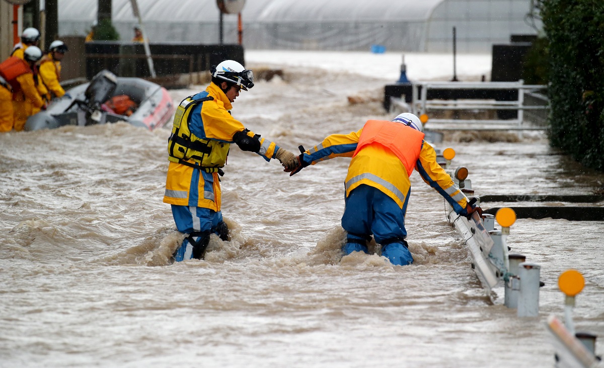 写真・図版 : 鬼怒川が氾濫した現場で、ガードレールにつかまりながら救助に向かおうとする茨城県警の救助隊＝2015年9月10日、茨城県常総市