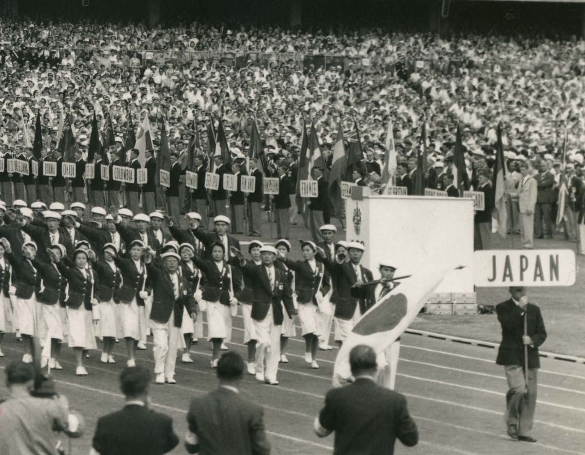 写真・図版 : メルボルン・オリンピックの開会式入場行進で開会宣言をした英国エディンバラ公に右手を挙げる田畑政治団長と選手たち＝1956年11月22日