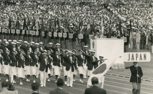 写真・図版 : メルボルン・オリンピックの開会式入場行進で開会宣言をした英国エディンバラ公に右手を挙げる田畑政治団長と選手たち＝1956年11月22日