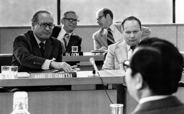 写真・図版 : 使用済み燃料の再処理をめぐって難航した日米核燃料交渉。スミス米国首席代表（左）と向き合うのは、日本の宇野宗佑科学技術庁長官（後ろ姿）＝1977年8月29日、東京・外務省