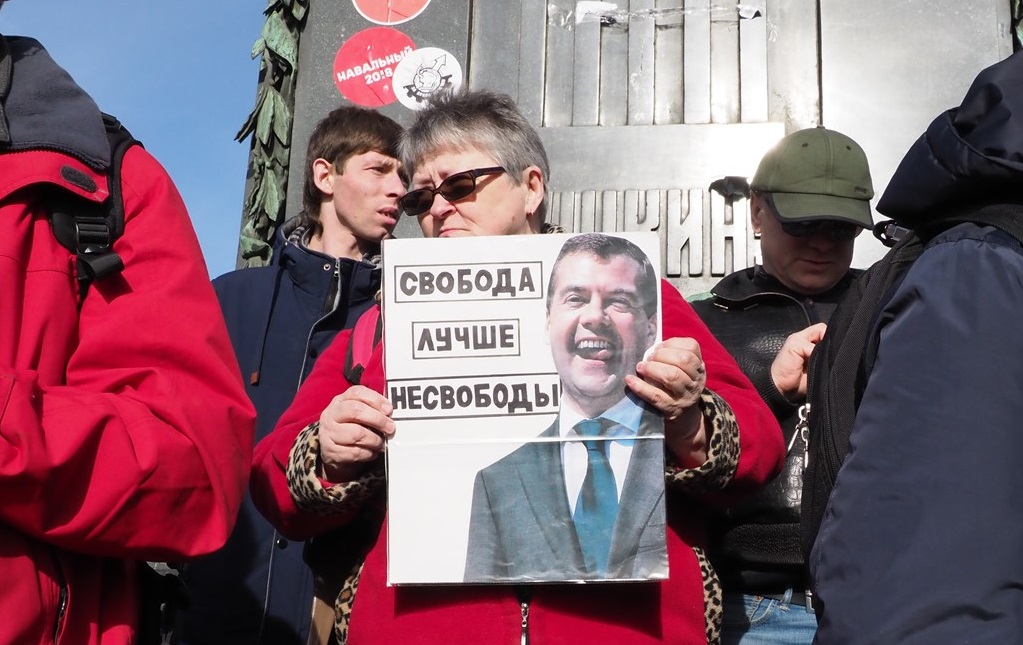 写真・図版 : メドベージェフ首相の蓄財を風刺する写真を掲げるロシアの反政府デモ＝2017年3月26日、モスクワ