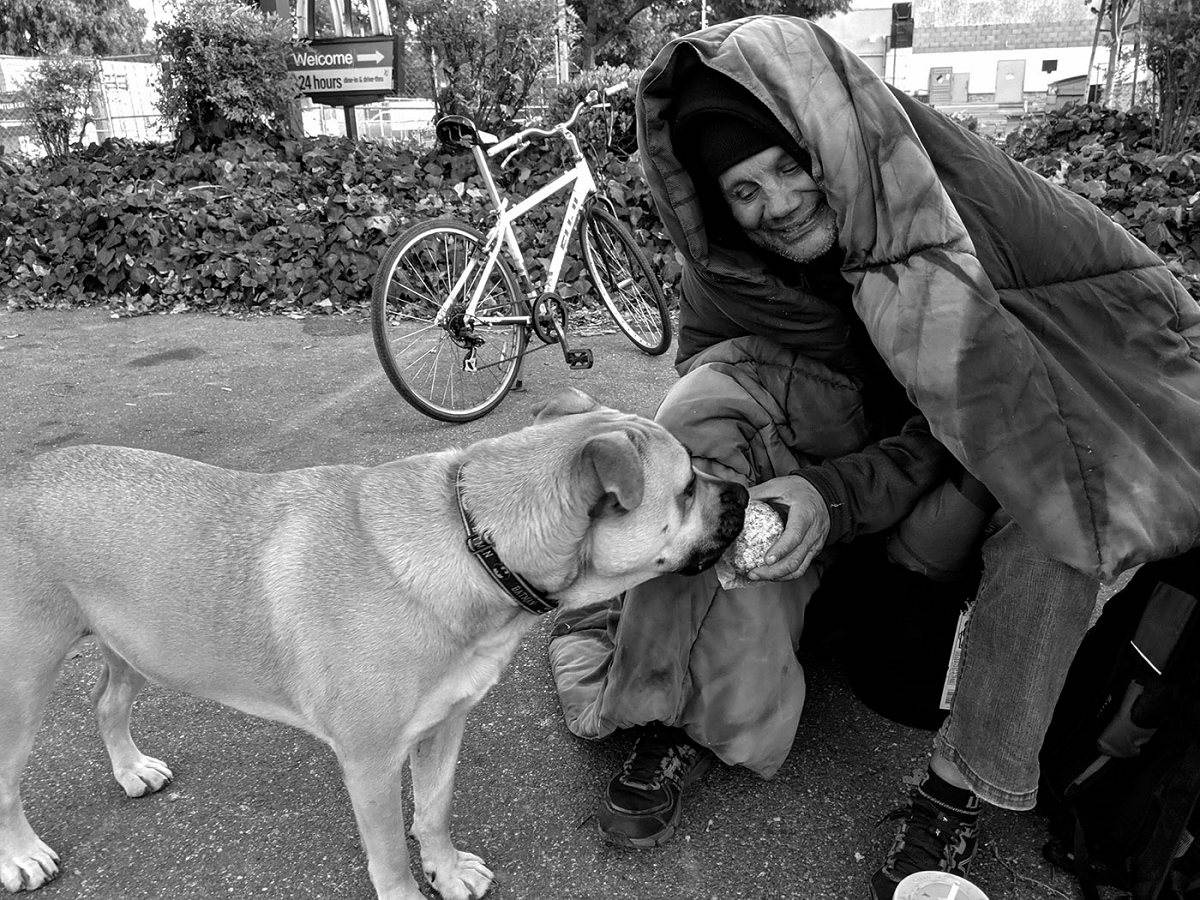 写真・図版 : ホームレスの男性にハンバーガーをもらうカリー。肉だけをくれるのを辛抱強く待つ© Eugene Fisher