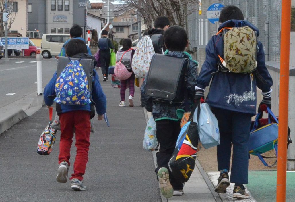 写真・図版 : 来月2日からの休校が決まった鶴岡市で、置いてあった教材など多くの荷物を抱えて下校する児童たち＝2020年2月28日、山形県鶴岡市