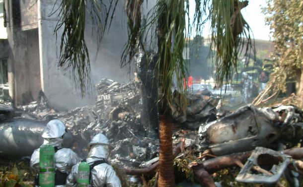 写真・図版 : 米軍ヘリが墜落した沖縄国際大学の現場。機体は炎上し、原形をとどめていない。後ろはヘリがぶつかった1号館 ＝2004年8月14日、沖縄県宜野湾市 

